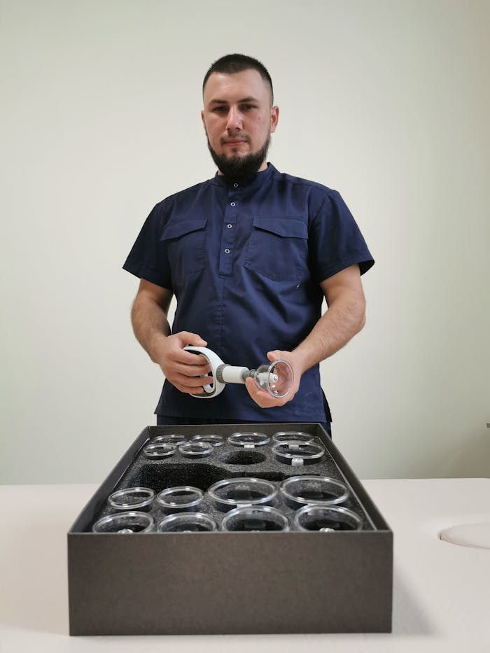 about-01 A male practitioner in a blue shirt prepares cupping therapy equipment in an indoor setting.
