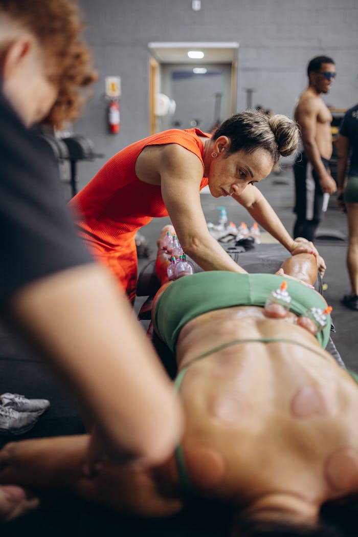A therapist administers cupping therapy on an athletic individual in a gym setting.