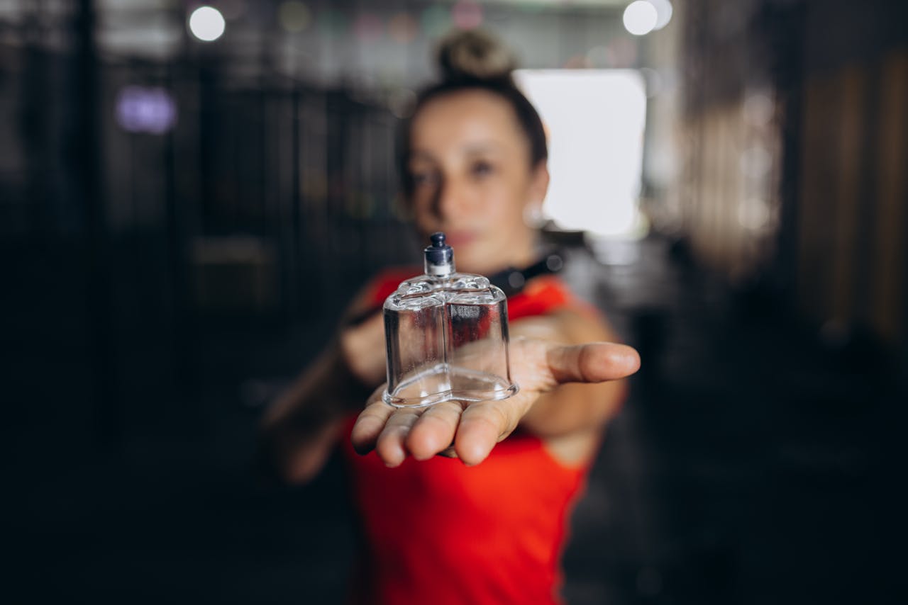 our-services-3 Focused shot of a woman holding a cupping jar in a gym setting, emphasizing recovery and wellness.