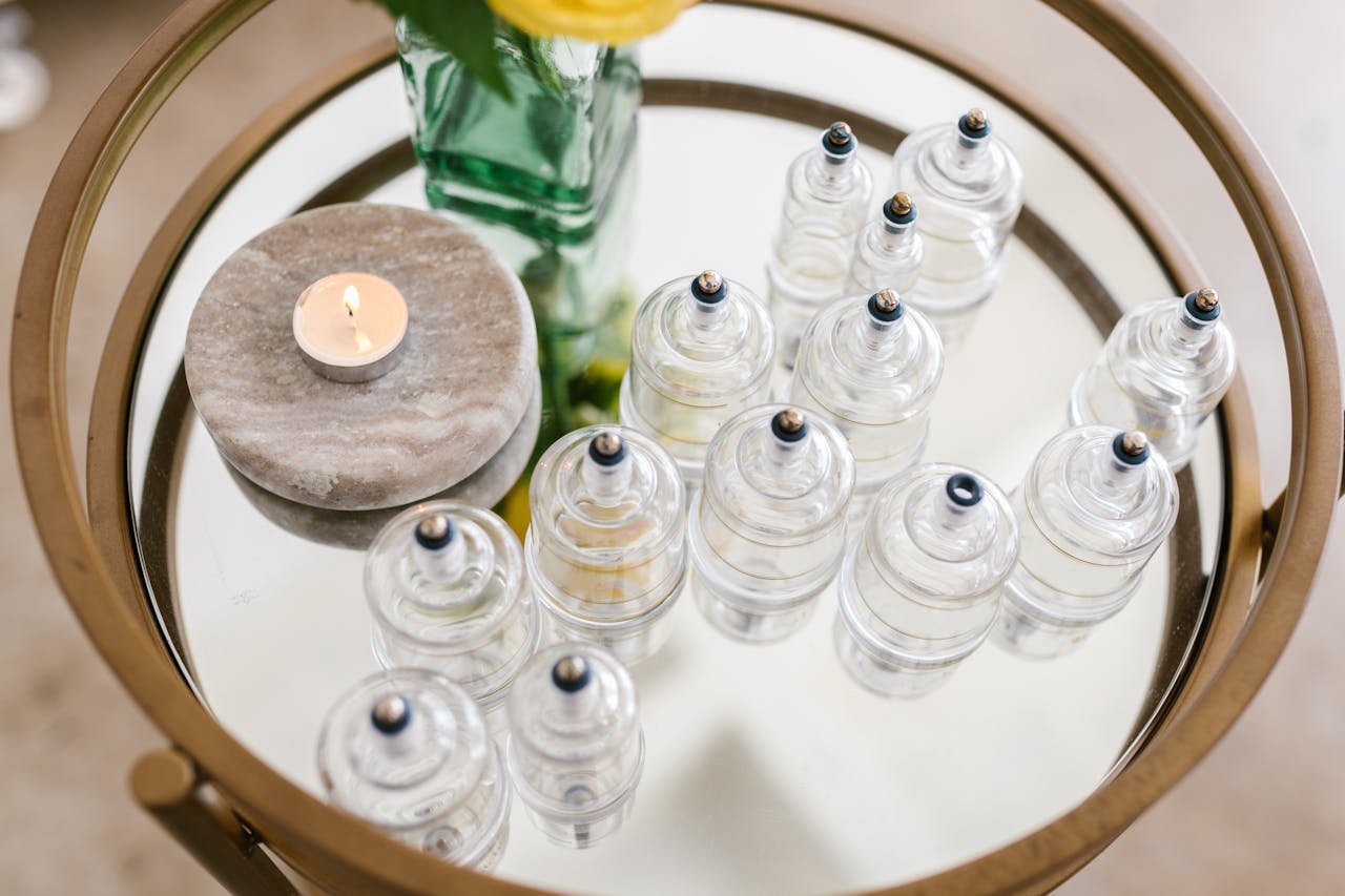 our-services-2 A stylish arrangement of glass cupping jars on a mirrored table with a candle and flowers, ideal for spa settings.